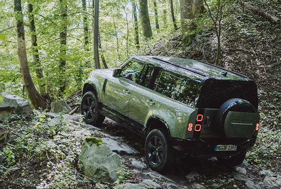 Ein grüner Geländewagen fährt durch den Wald.