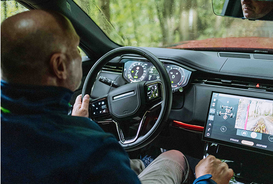 Ein Mann am Steuer lenkt einen Geländewagen durch den Wald.
