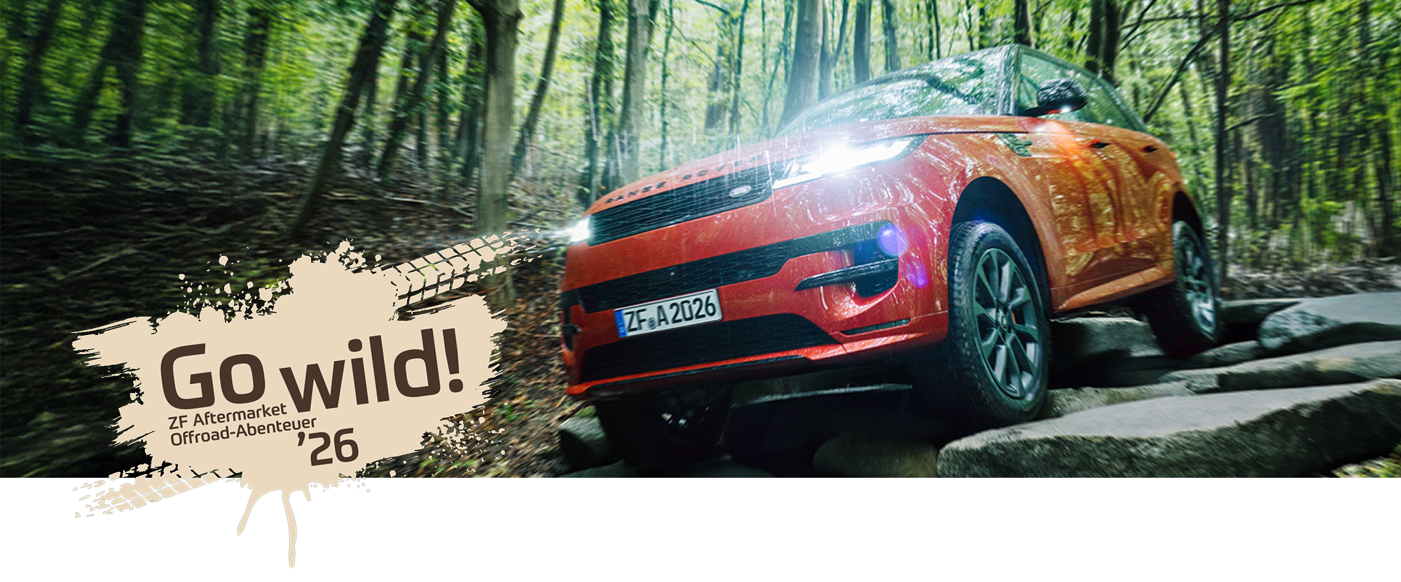Ein roter Geländewagen rollt eine steinige Straße durch den Wald auf uns zu. Links ein Fleck mit Reifenspuren und dem Schriftzug: 'Go wild! 2026' ZF Aftermarket Offroad-Abenteuer.